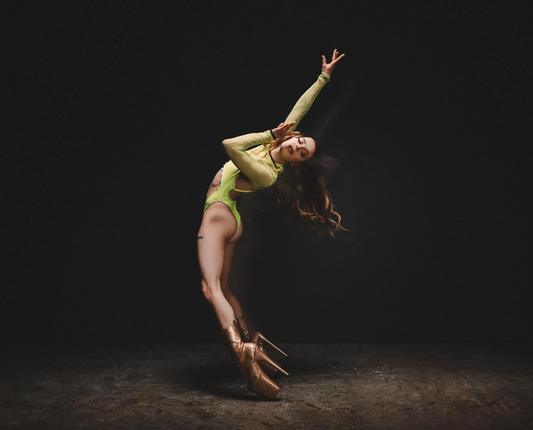 Performing Artist Isabella Condello dancing in a bright green outfit in a dimly lit room