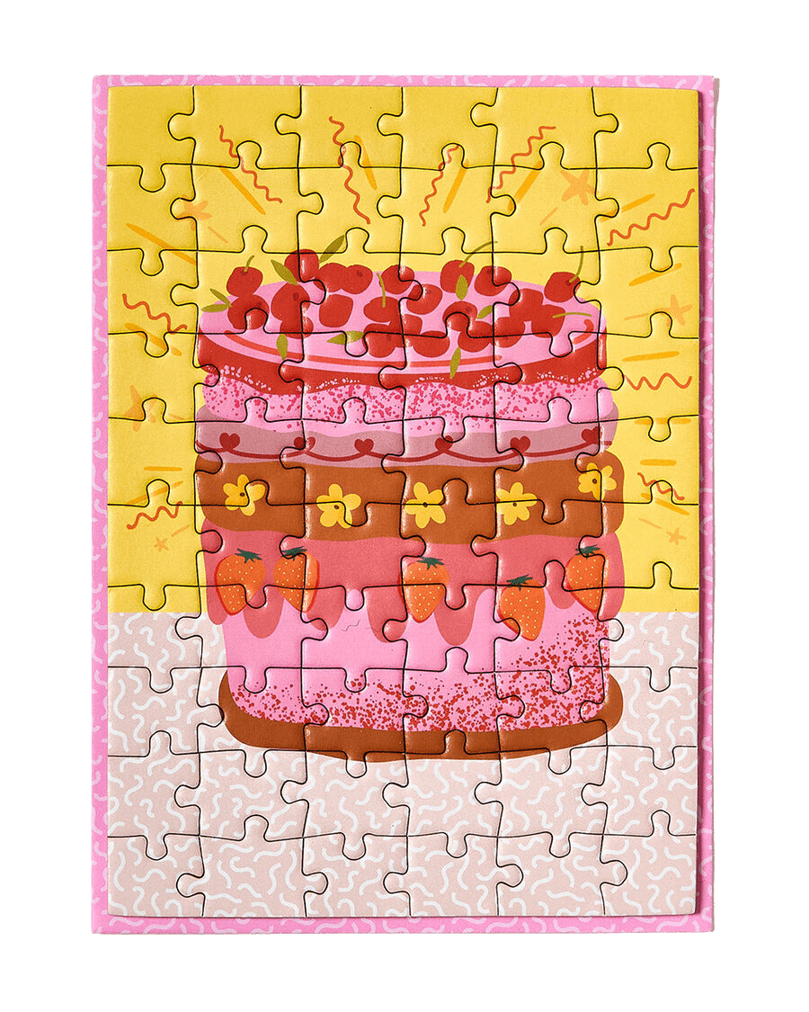 Greeting card puzzle: A super cute design of a multicoloured retro cake with flowers, strawberries and cherries on a yellow background with tiny squiggles around the outside.
