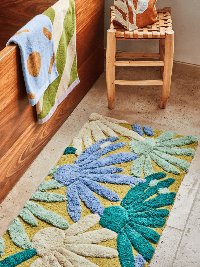 Margarita Bath Mat by Mosey Me. A long rectangular bath runner with blue, white and dark green half flowers with a pale green background.