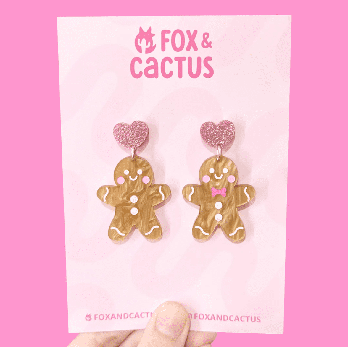 Cute as a button: These Fox & Cactus Gingerbread dangle earrings feature a pink glitter heart at the top & a small gold hook that links to a super cute gingerbread man with white & pink accents including a bow tie and rosie red cheeks.