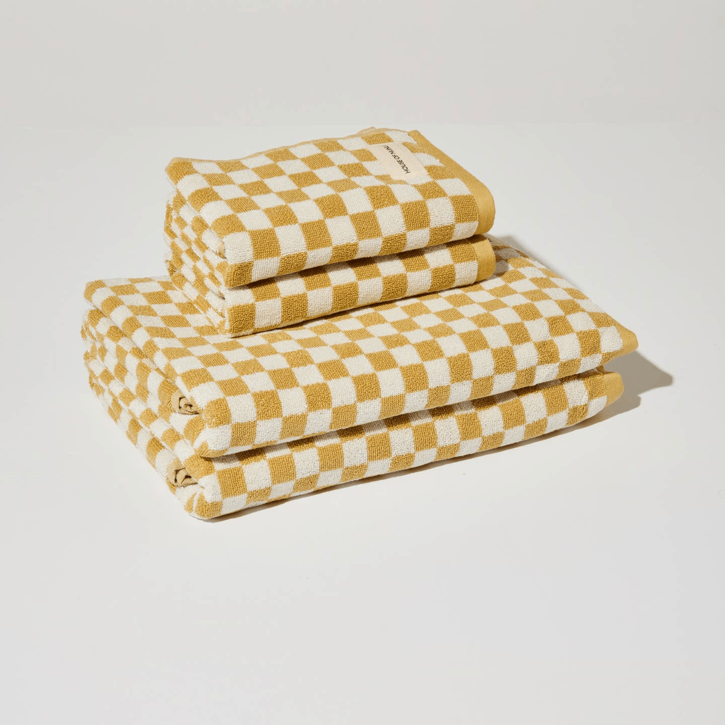 A pile of yellow and white check hand and body towels folded in a neat pile together.