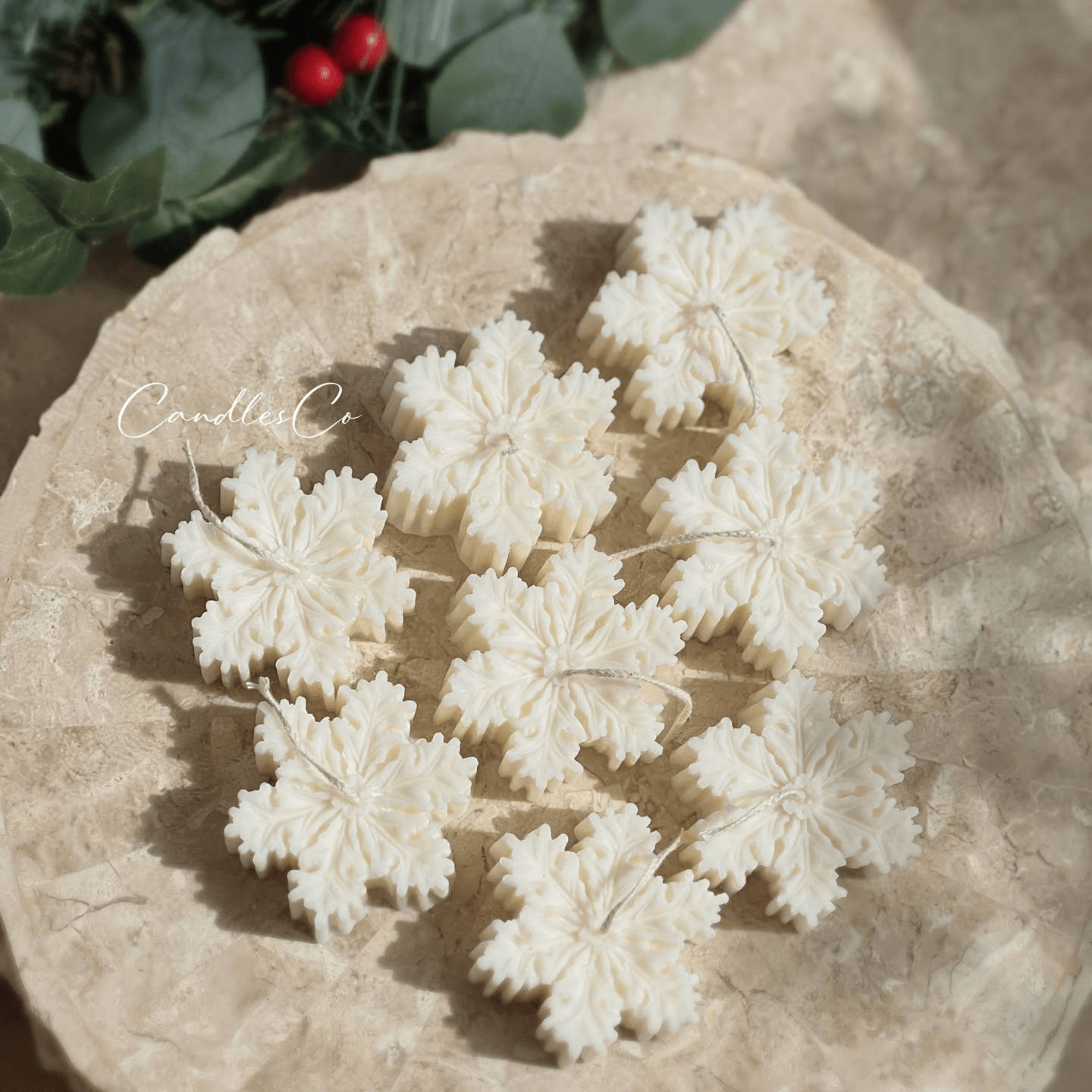 A collection of 8 beautiful handcrafted, pristine white snowflake candles on a terracotta plate.
