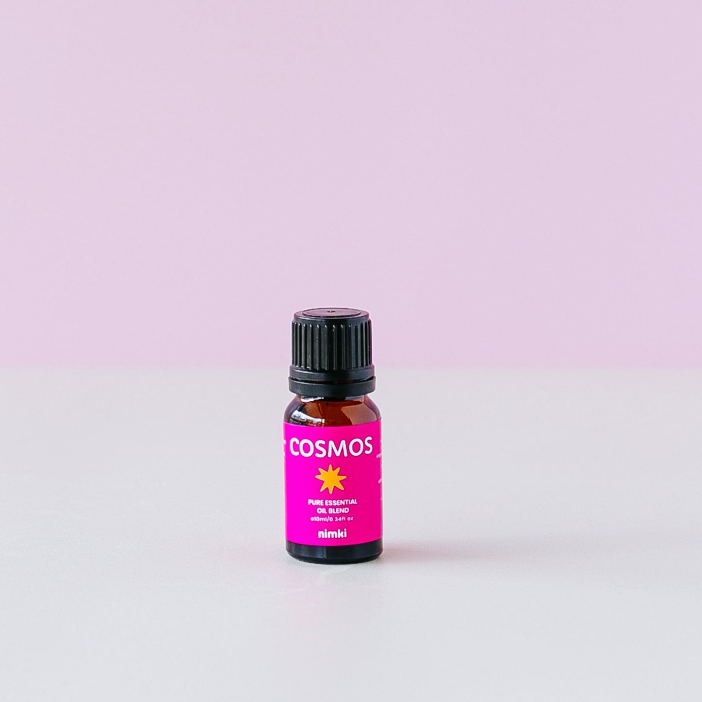 Nimki COSMOS essential oil blend: a cute amber bottle with a hot pink label and white writing that reads "COSMOS" with a yellow star underneath.