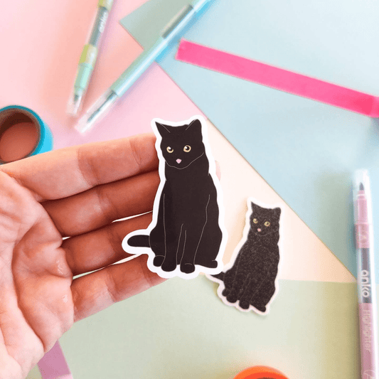 A super cute black cat vinyl sticker, his eyes are gold with a tiny pink nose. 