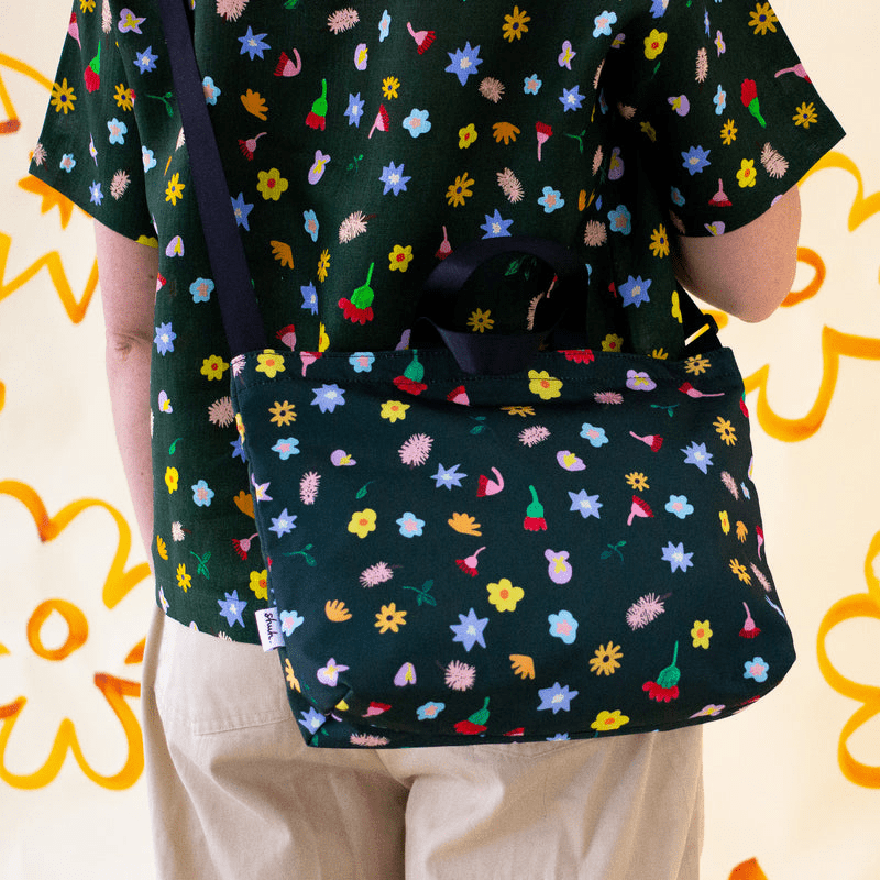 Shuh Lee's vibrant handbag with shoulder strap: A joyful design with a forest green background and tiny pieces of nature scattered across including bottle brushes, daisies, leaves and other Australian fauna. 