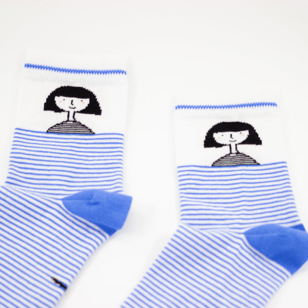 Shuh Lee Girl Striped Socks: Adorable white socks with a bold blue stripe extending from the toe to mid-calf. The heel features the word "shuh," while the ankle showcases a tiny black-and-white portrait of Shuh with her signature bob haircut and a sweet smile.