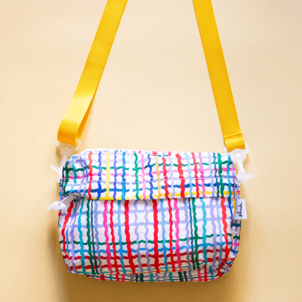 Shuh Lee's Wave Everyday Shoulder Bag: a small, rectangular bag with a white background and a cross hatch of colourful, wiggly stripes in every colour. 