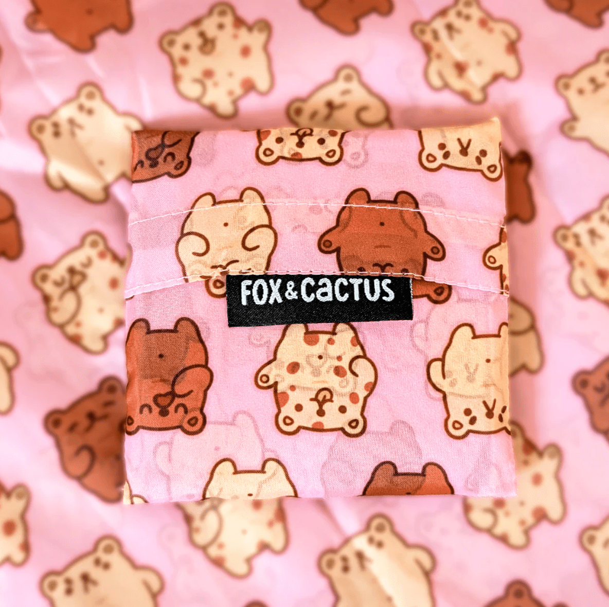 Super cute, Baby Bear Reusable Tote Bag by Fox and Cactus. This bag has a pink background with alternating light and dark tiny teddies across the front. 